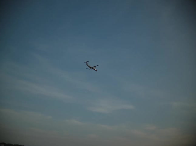 An airplane is flying over the sea with the city skyline in the background