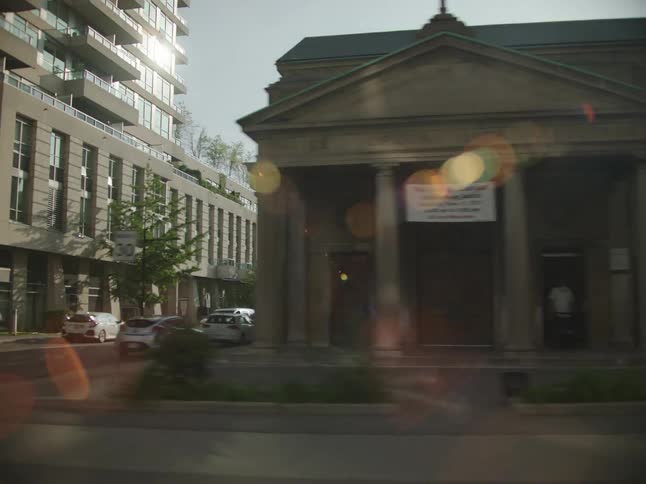 Pedestrian crosses street between modern building and landmark building near downtown