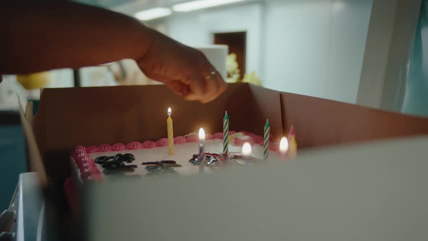 A person lights the candles on the birthday cake
