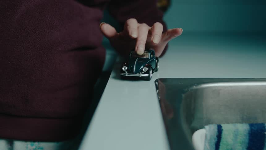 A person pushes the toy car off the counter