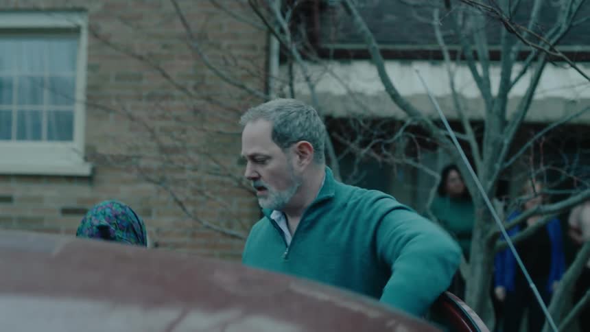 Man holding the car door open and an elderly lady getting out