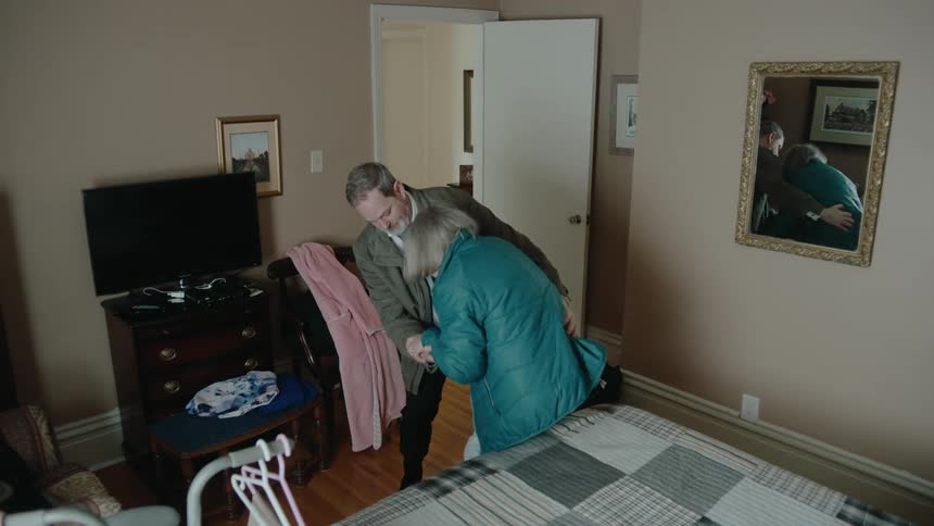 A man helps an elderly women into an apartment and they get angry with one another
