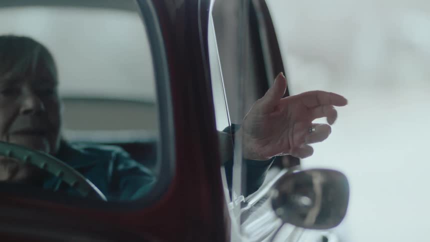 A woman waves her hand out the car window