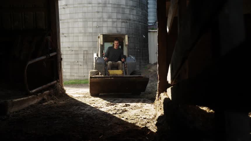 A man drives a tractor past the silo