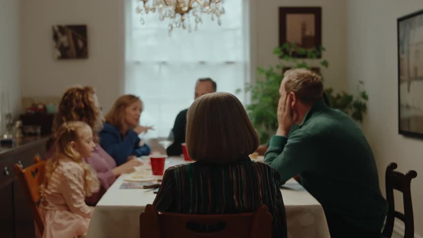 Family sitting at a table talking and a lady getting up