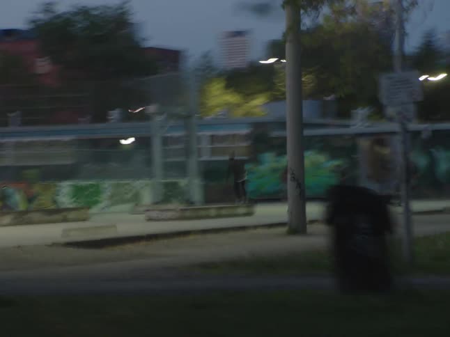 City street at dusk with a recreational square with skateboarders