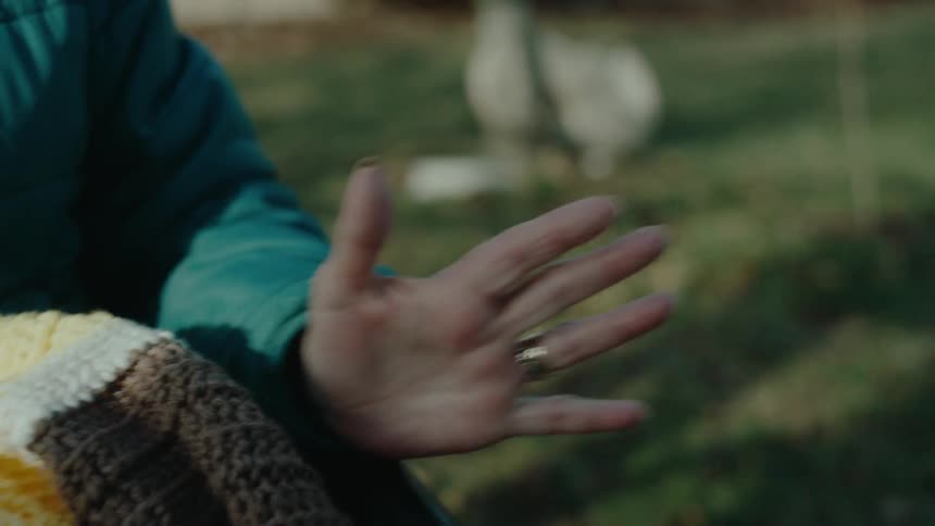 An old woman is wheeled through a yard