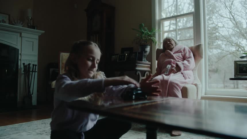 A young girl plays with a toy car while her grandmother sits nearby