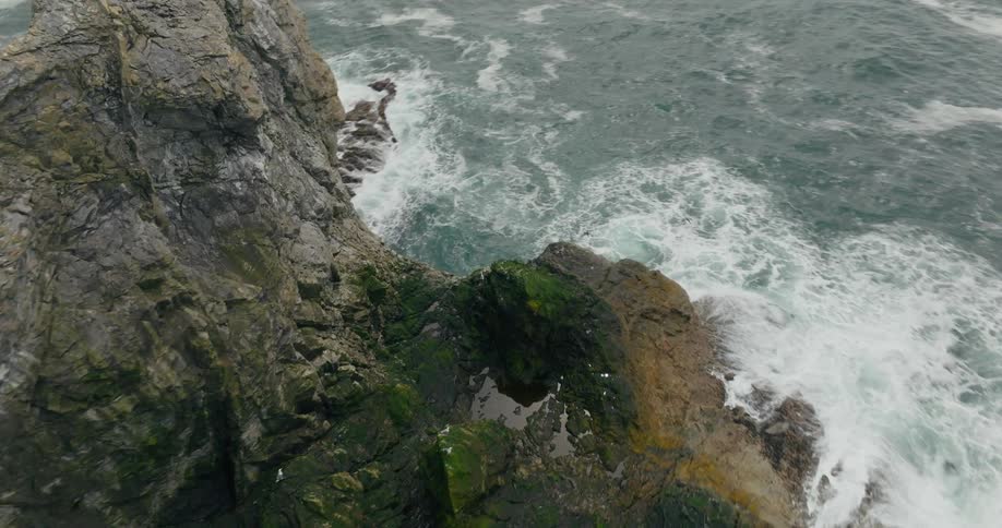 Waves splash against an arch rock formation