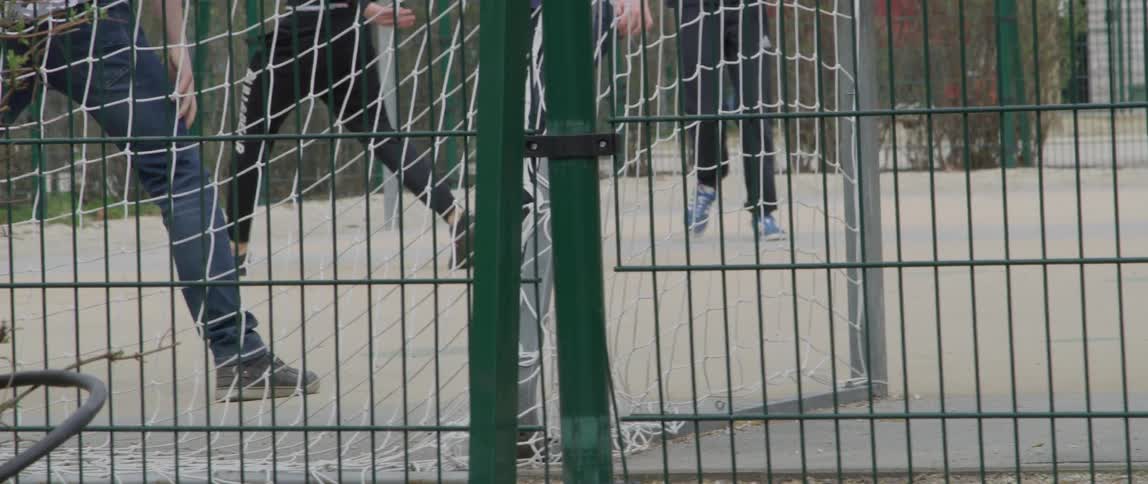 Legs of some boys who are playing soccer on a concrete court