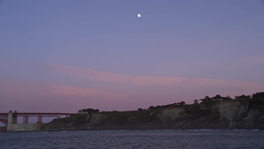 Panorama of the seaside coast with the golden gate bridge and a purple sky with the moon