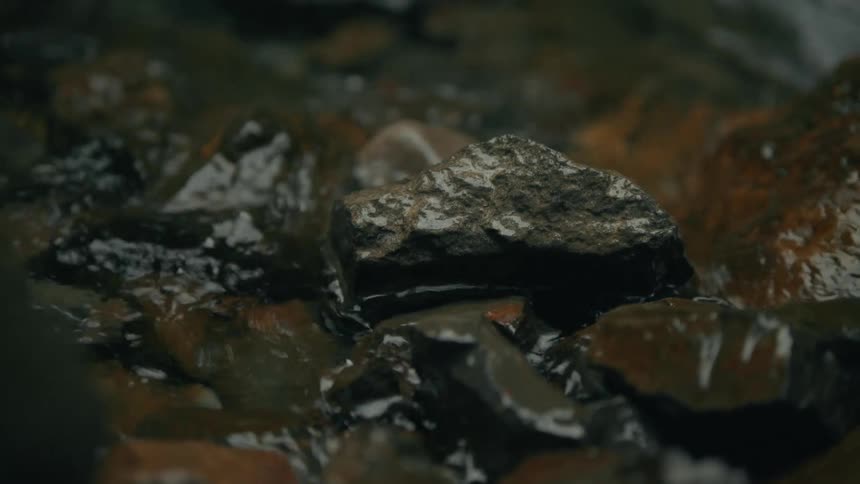Closeup on rocks in a lake with water draining away