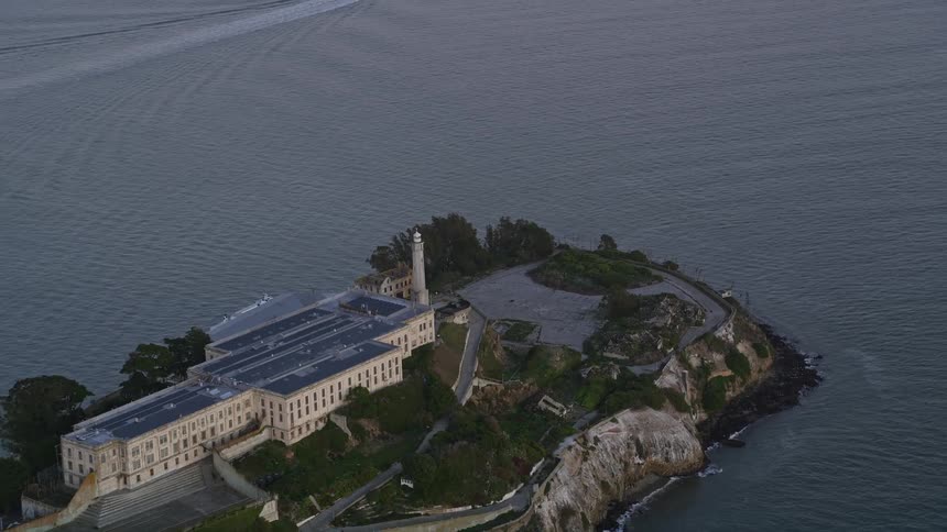 Aerial panorama of a prison on an isolated island in the middle of the sea with a boat in the background