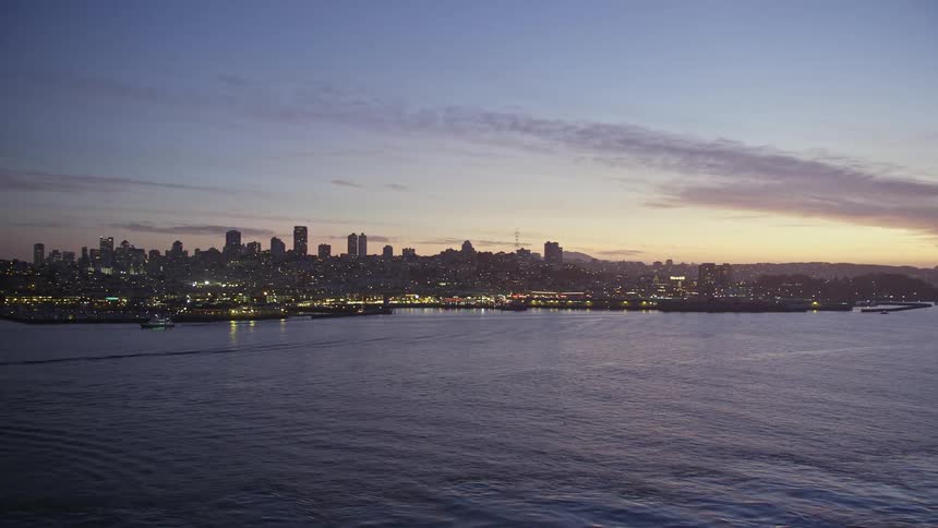 Aerial panorama of an illuminated seaside metropolis against a purple sky