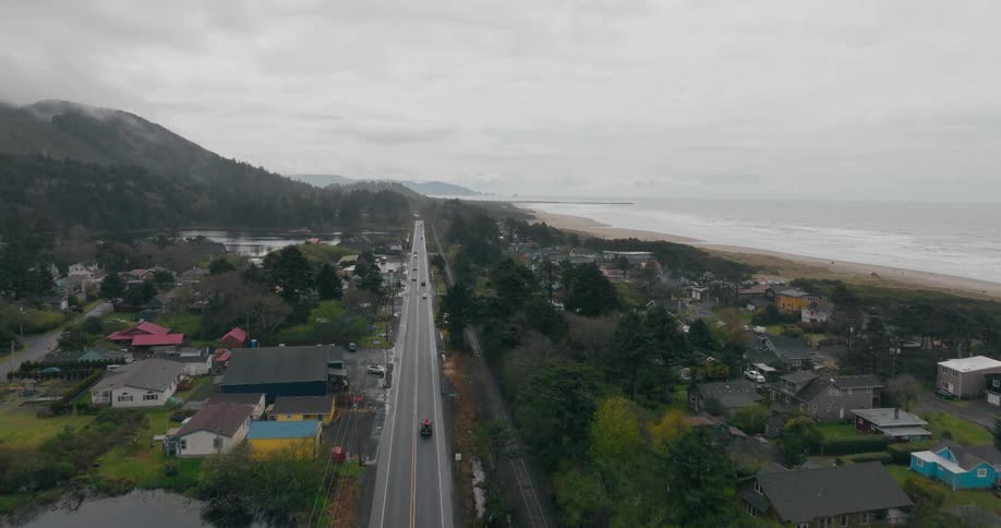 Aerial panorama gave a highway extension on the edge of urban houses with a beach and mountains in the background