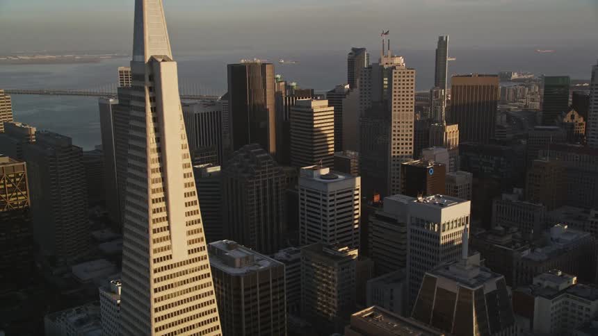 Aerial panorama of skyscrapers of a metropolis with morning sunlight reflection and seaside
