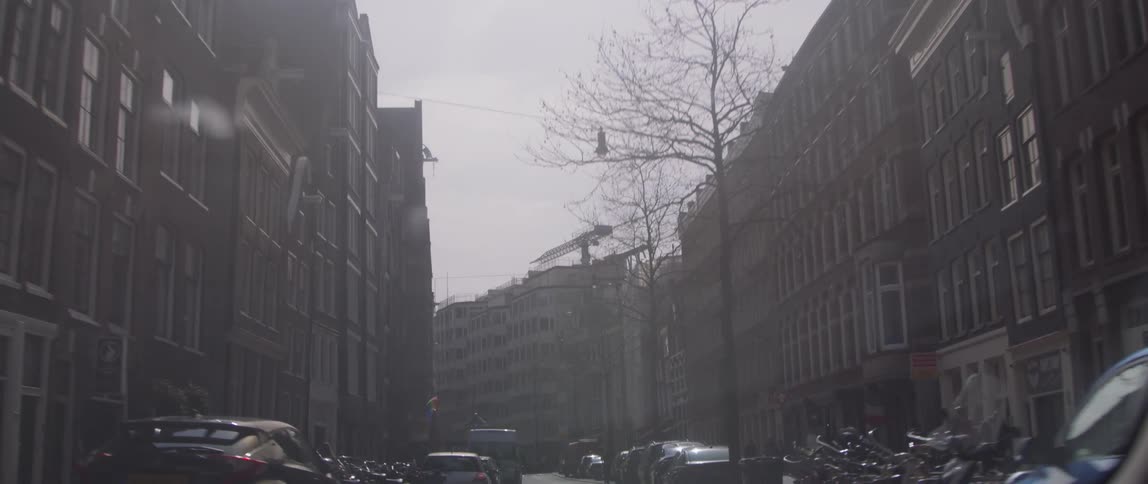 Parked vehicles line street between apartment buildings near a construction site