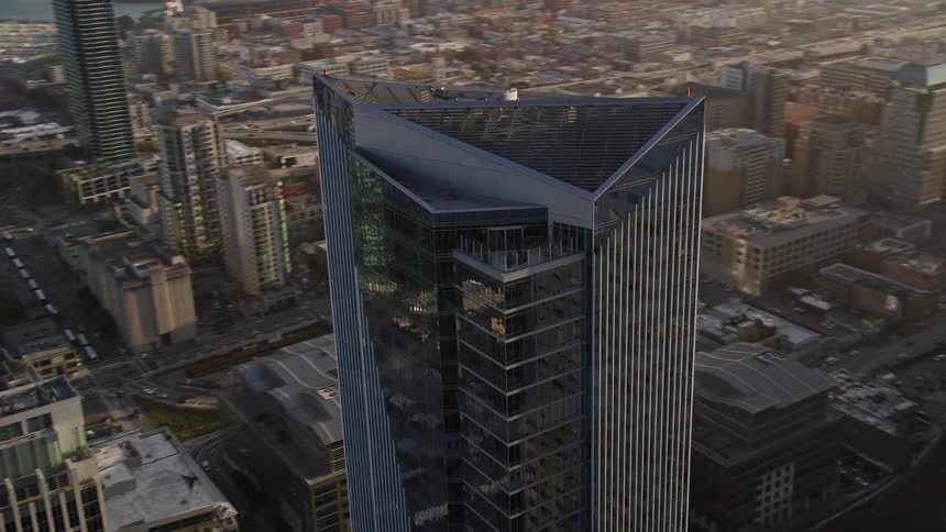 Aerial view of the exterior architecture of a modern mirrored skyscraper in a metropolis with the reflection of evening sunlight