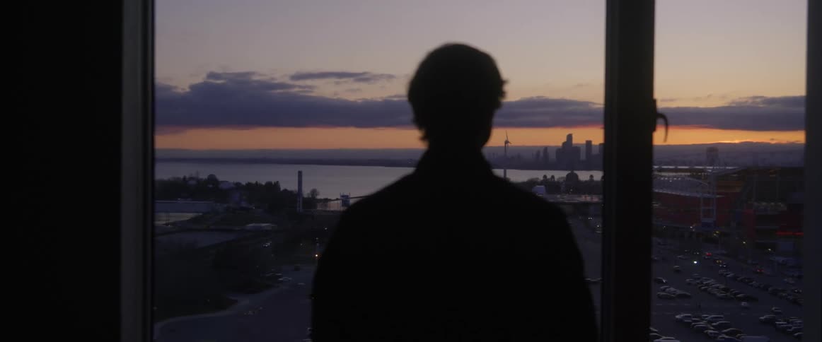 A man gazing at a city skyline through a large glass window