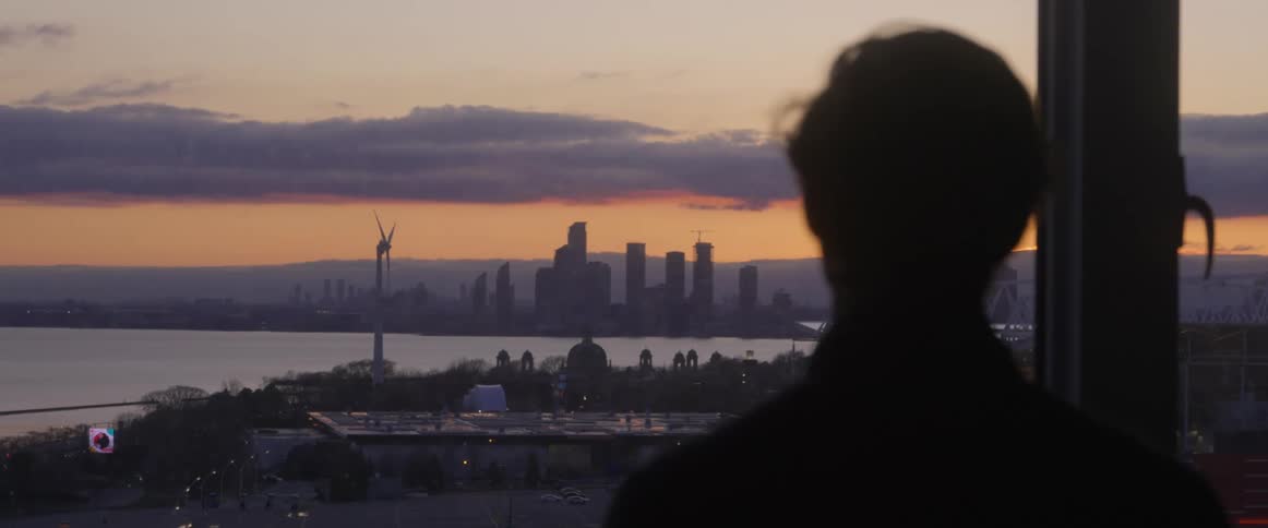 A man gazing at a city skyline through a large glass window