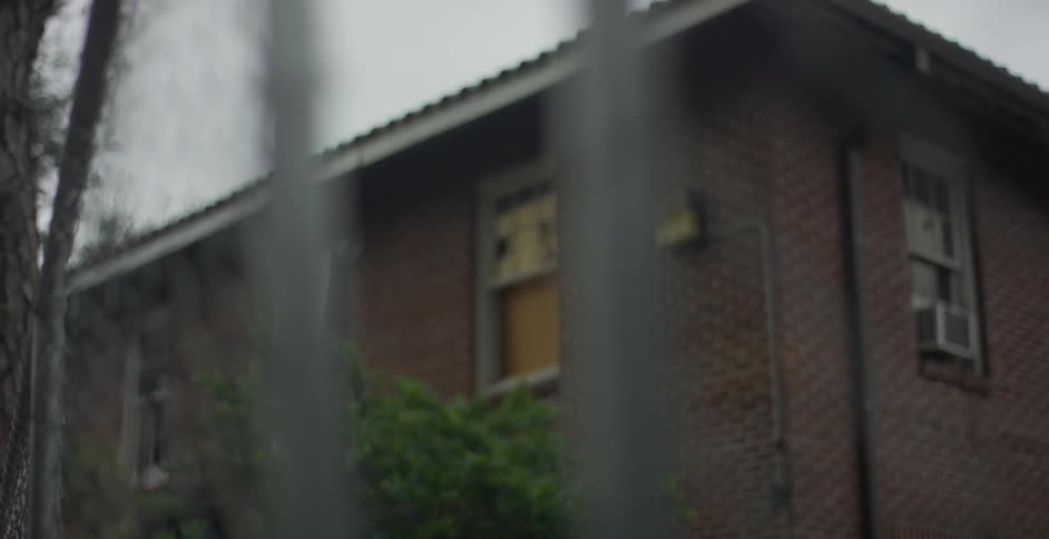 A metal fence in front of a brick house under an overcast sky