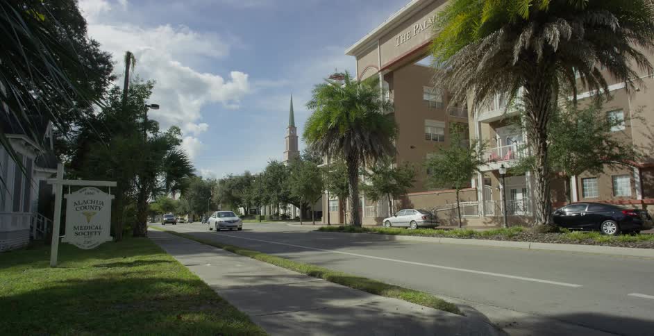 Some cars driving very slowly on an asphalt street in an urban region