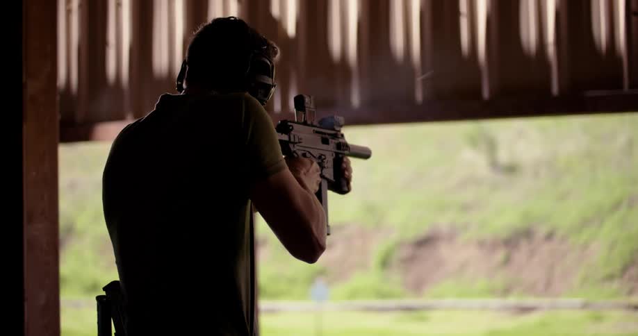 Man with protective glasses and a noise headset shooting a gun in a training center