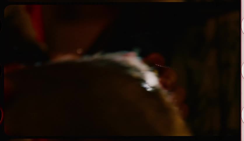 Close up of a barber shaving the head of a client in a dimly lit room