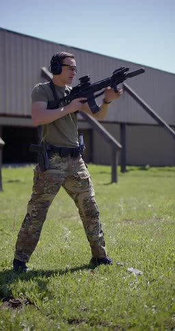 A man standing at a shooting training range is shooting a gun and reloading it