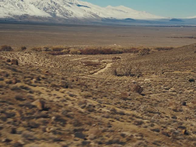 A vehicle drives down a road through a desert