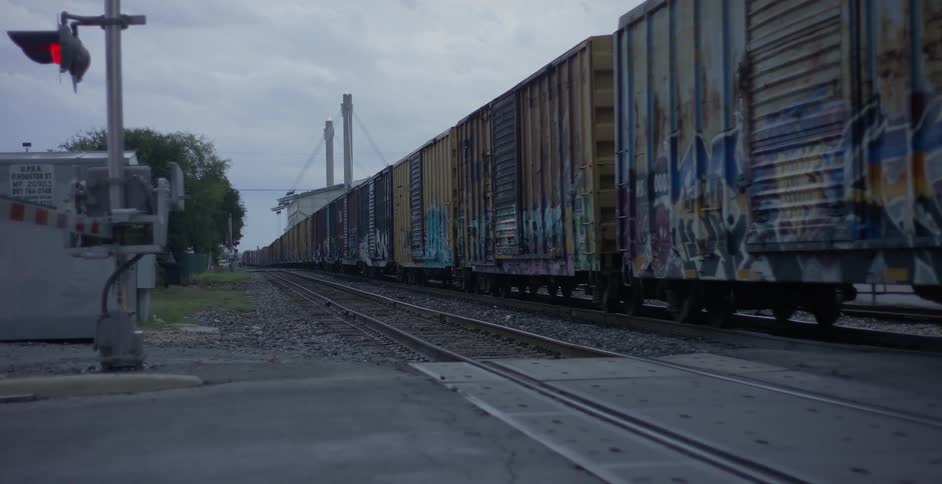 A train covered in graffiti rolls down a track