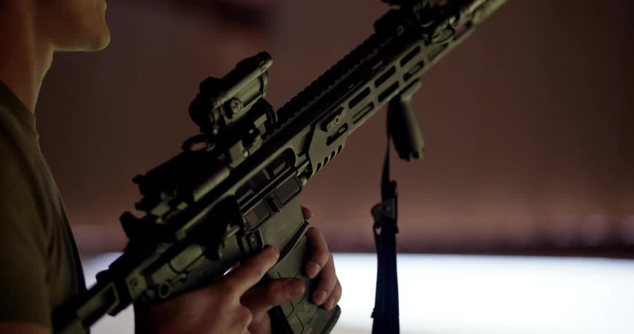 A man loads a magazine into a firearm and aims it