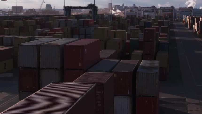 Stacked shipping containers line loading dock with downtown in the background
