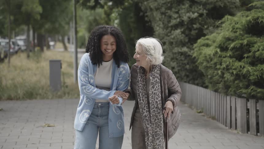 A young woman helps an elderly lady to cross the street