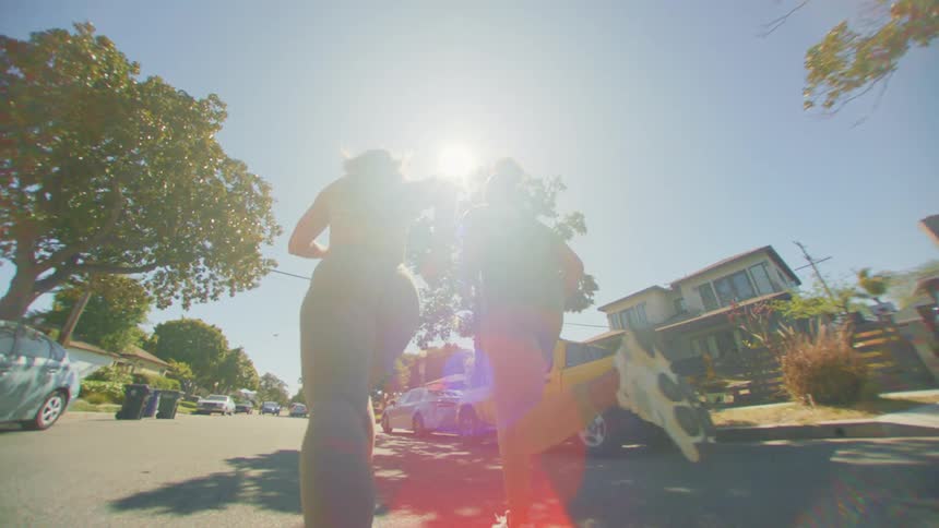 A man and a woman wearing sports outfits jog along the road