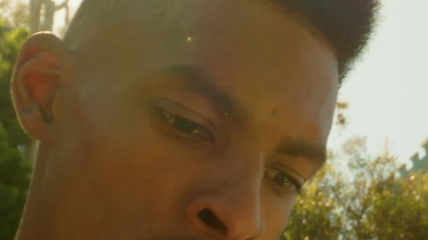 Portrait of a man in an openair environment with trees around and the reflection of sunlight
