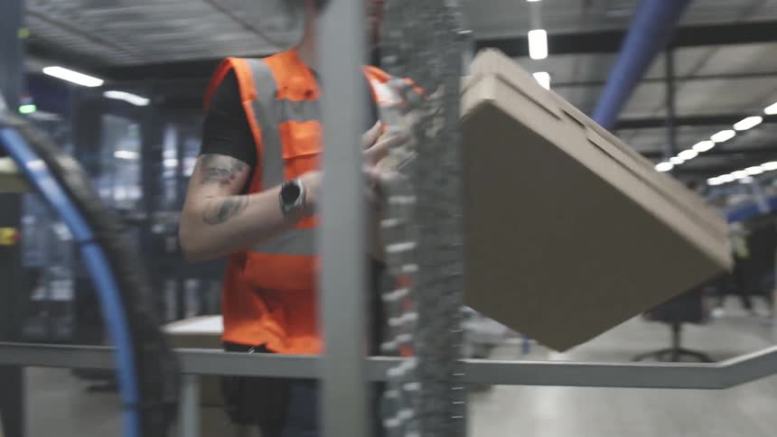A worker in a distribution warehouse moves a package