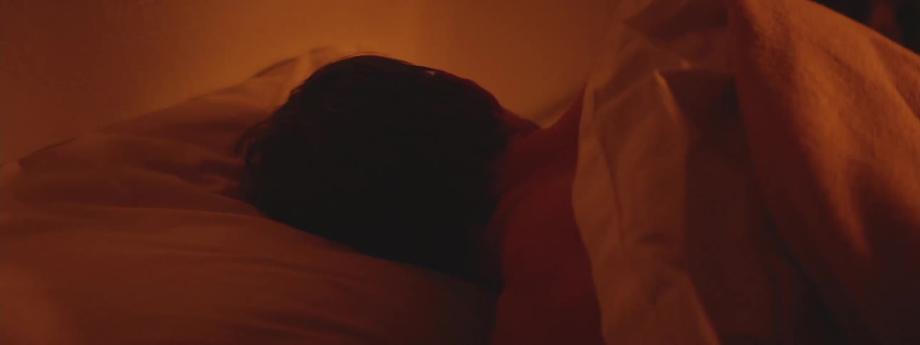 A man rolls around in a bed