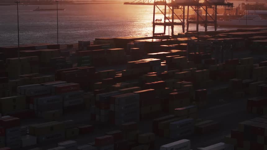 Stacks of containers sit in a port