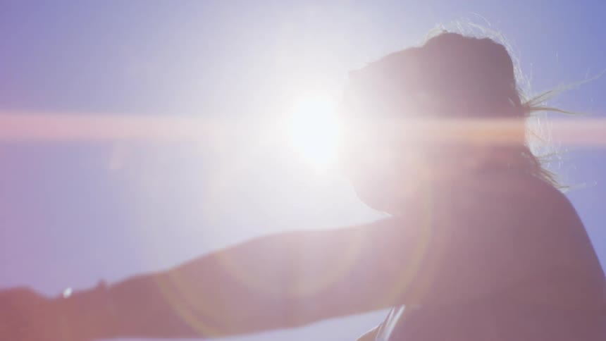 Portrait of a woman with sunglasses in an openair environment stretching her arm with an elastic band