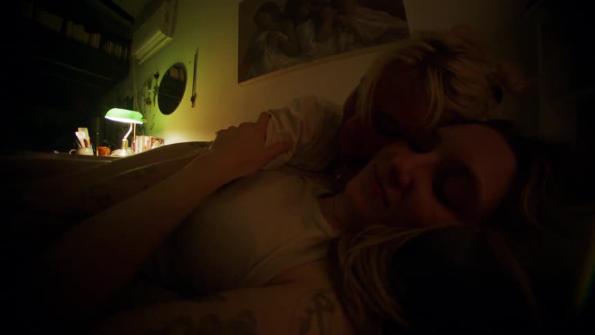 Two women cuddle together in bed