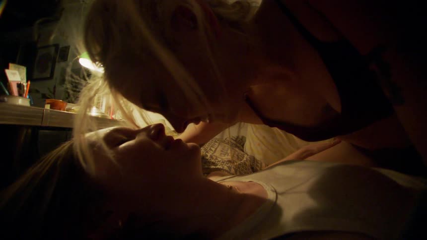 A happy lesbian couple makes out on the bed under the lamp light