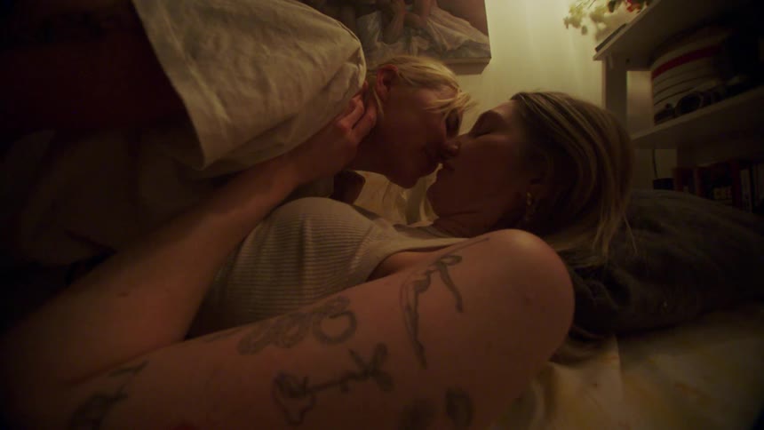 Two women lying down kissing each other affectionately