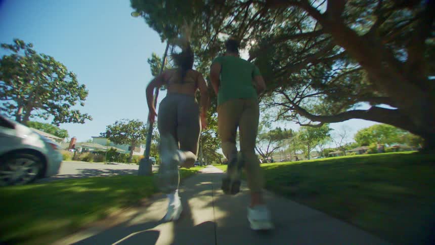 Two women are running together on the sidewalk