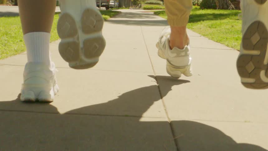 Closeup of two people running on the sidewalk