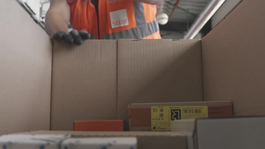 A worker is stacking packages in a box