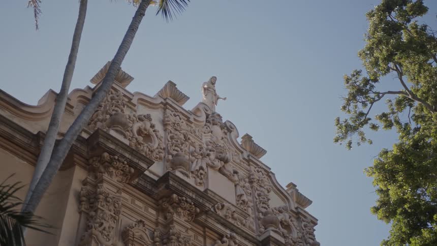 An old building sporting a statue sits next to trees