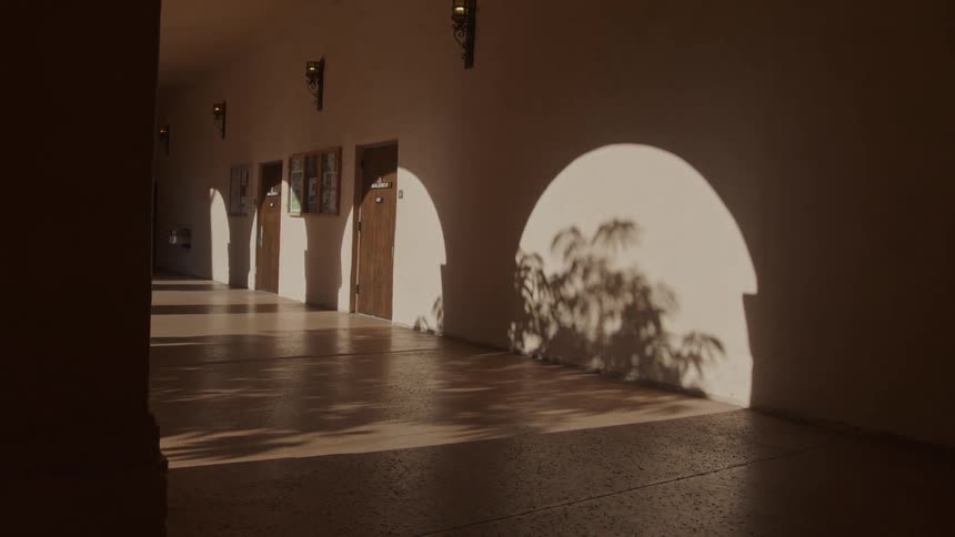 Sunlight entering openings in arcade creates bright arches against building wall