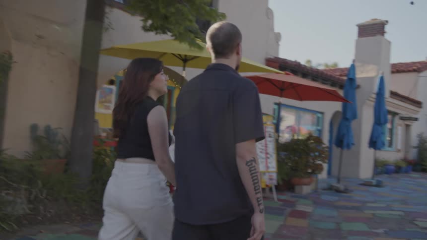 A couple walks through the spanish village art center holding hands