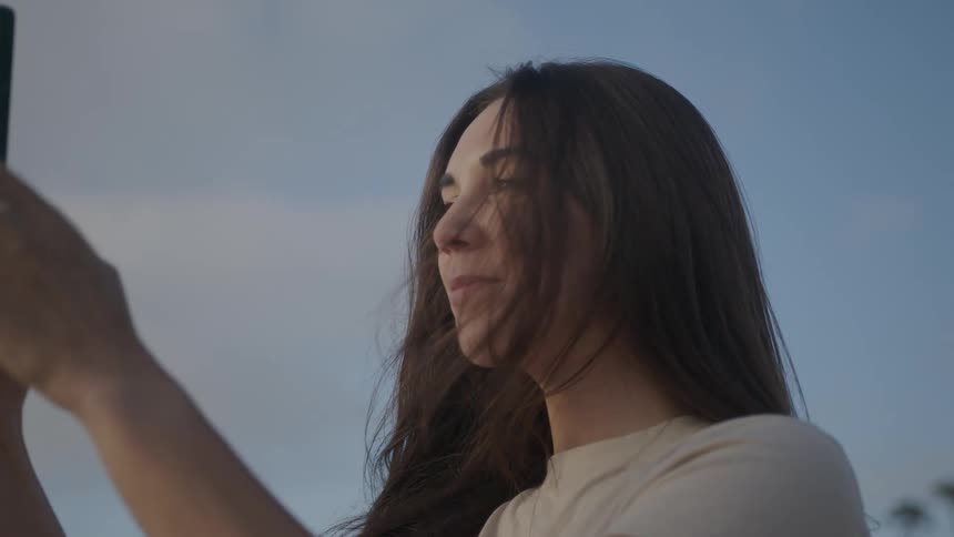 A woman holds a smartphone up to film or take picturestion